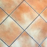 Piastrelle nere con fughe bianche, illustrate con un ingrediente della dispensa per la pulizia.